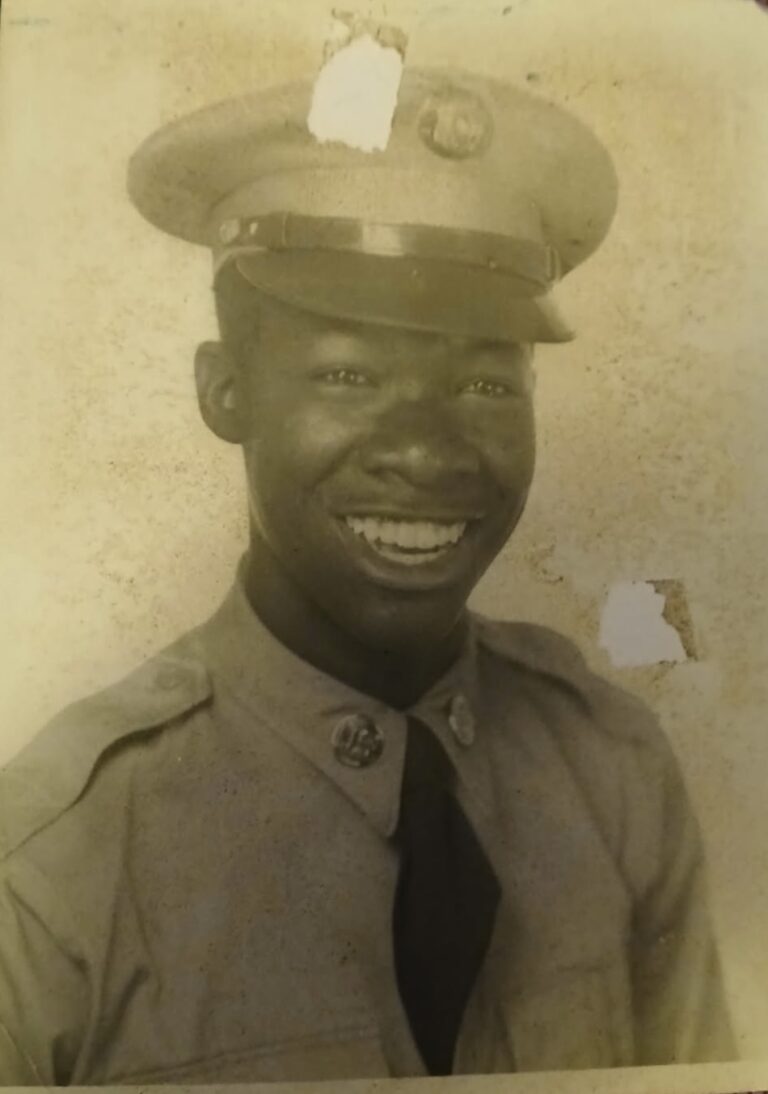 Smiling soldier in vintage military uniform.