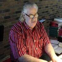 A man sitting at his desk in front of books.