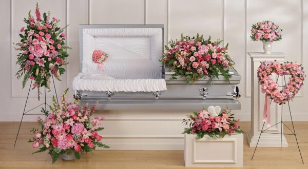 A casket with flowers in it sitting on top of a table.