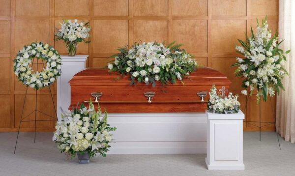 A casket with flowers in front of two other caskets.