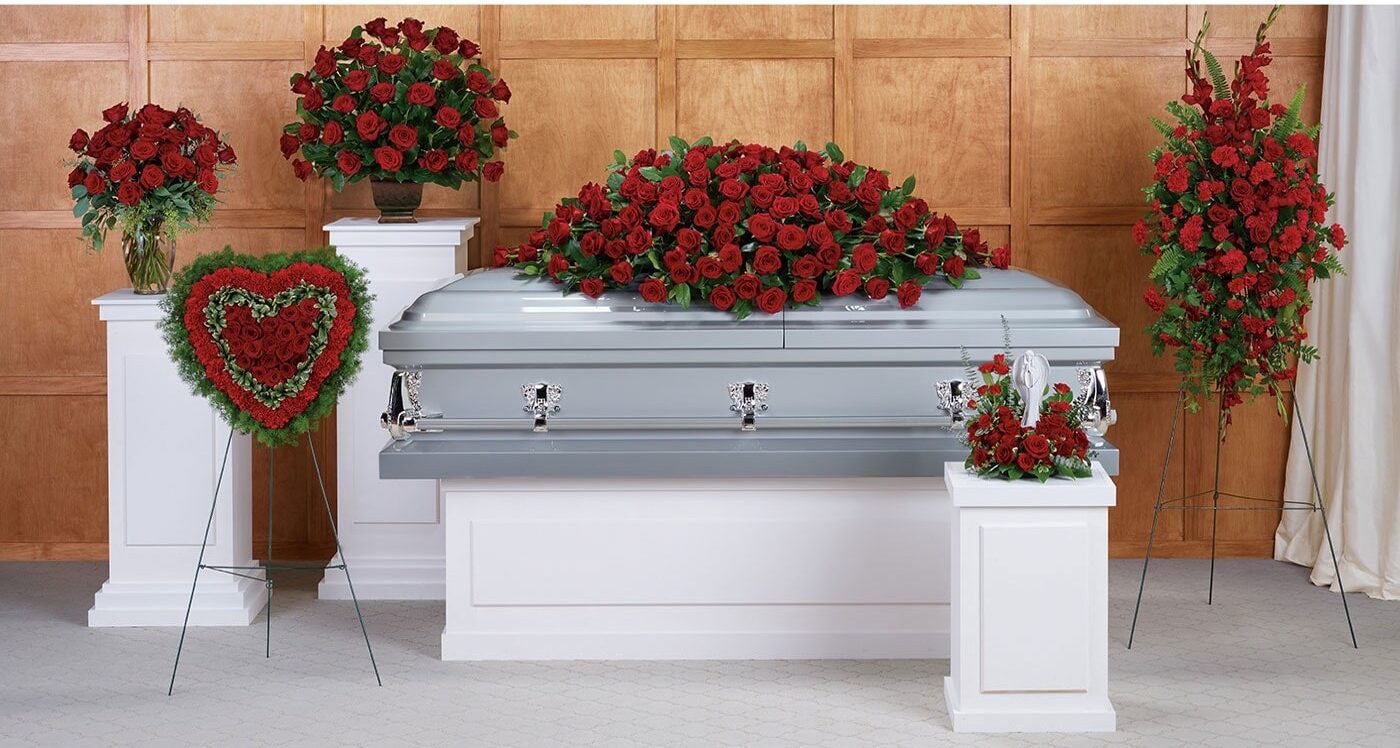 A casket with roses and a wreath on it.