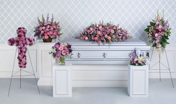 A white casket with purple and pink flowers.