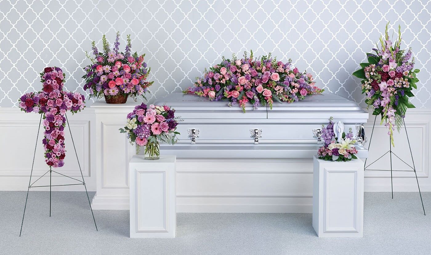 A white casket with purple and pink flowers.