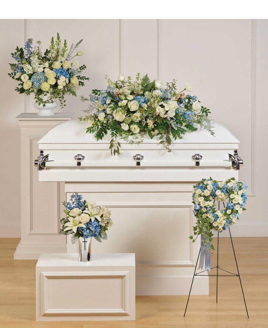 A white and blue casket with flowers in it.