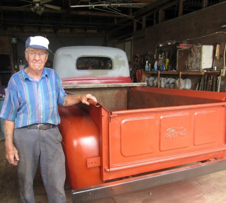 Man standing beside red Ford truck bed.