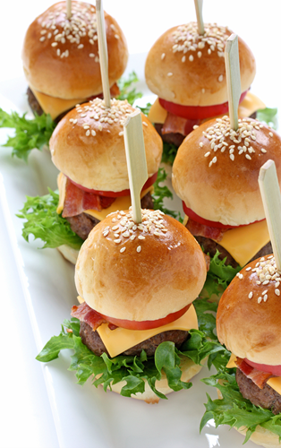 A plate of mini sandwiches with meat and cheese.