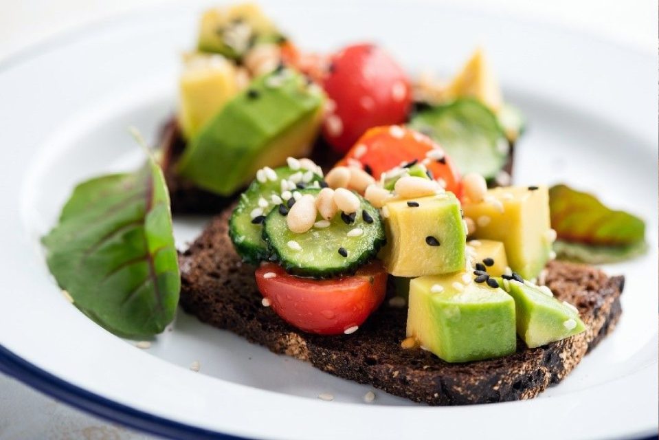 A plate of food with avocado and tomatoes on it.