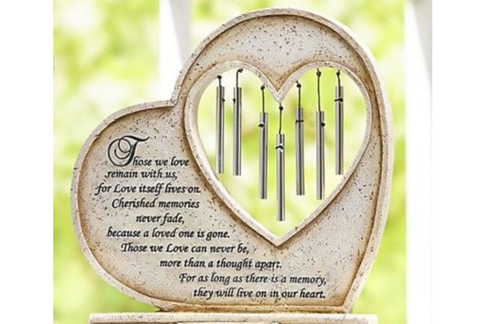 A heart shaped plaque with wind chimes inside of it.