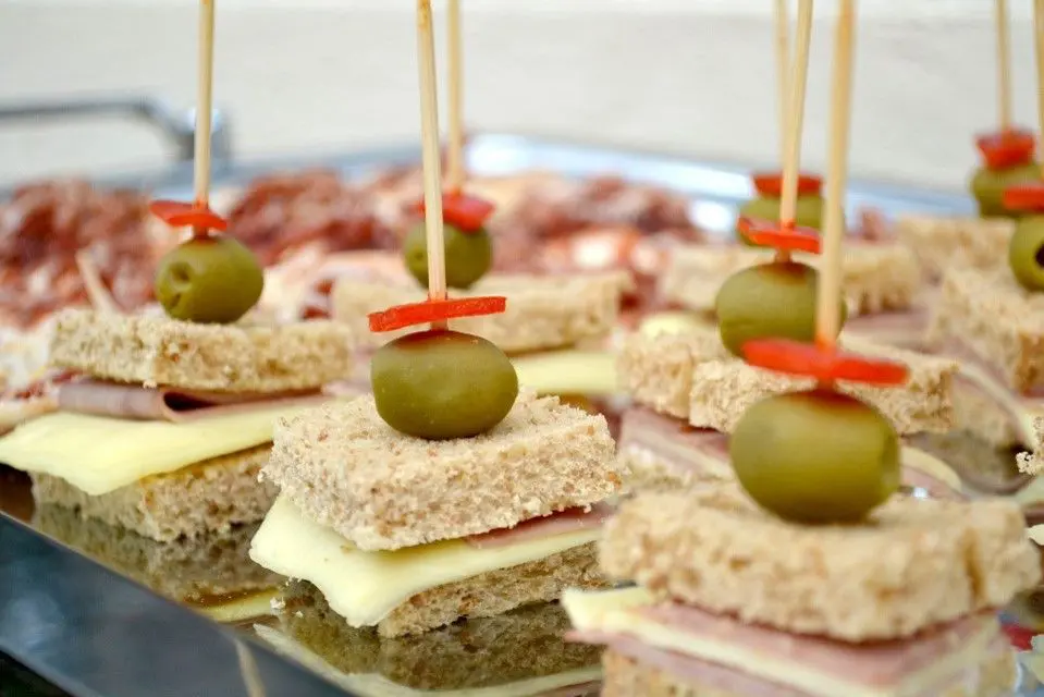 A tray of finger foods with toothpicks and olives.