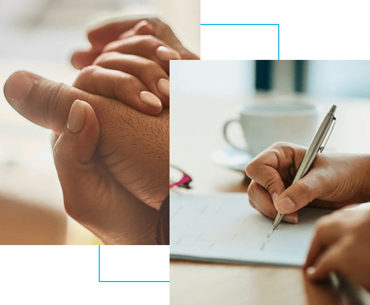 Two hands holding each other while writing on a piece of paper.