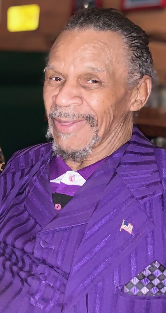 Smiling man in a purple striped suit.